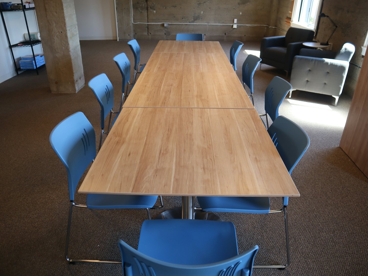 Moderna sala riunioni con un lungo tavolo in legno e sedie blu.